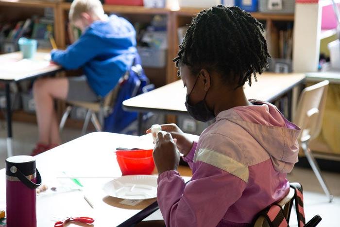 A student sites at a desk wearing a mask in a classroom