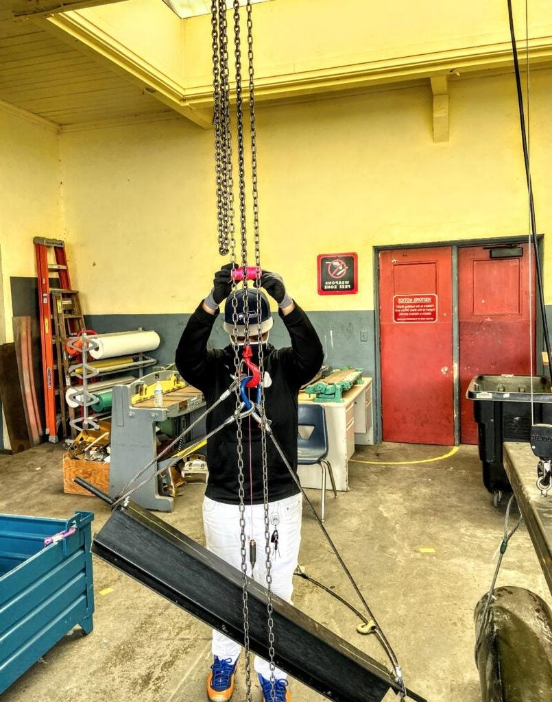 Trades program students working with a beam