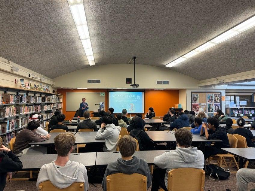 Students sitting in library listening to inventor speak about bluetooth technology