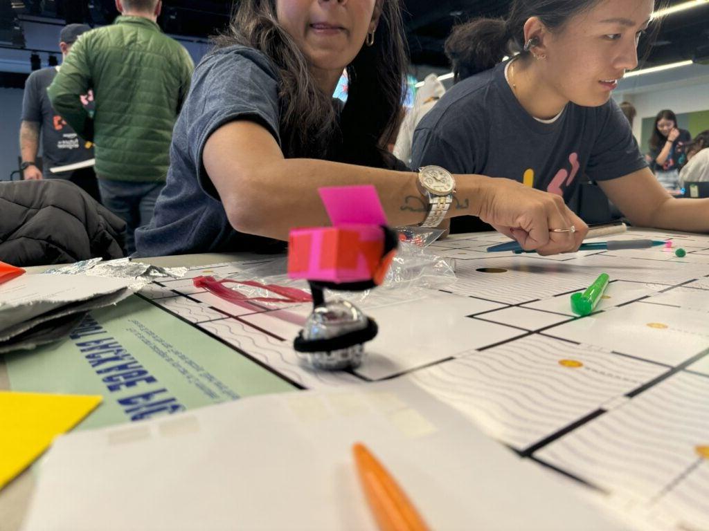 Teacher and student leaning over obstacle course for ozobot